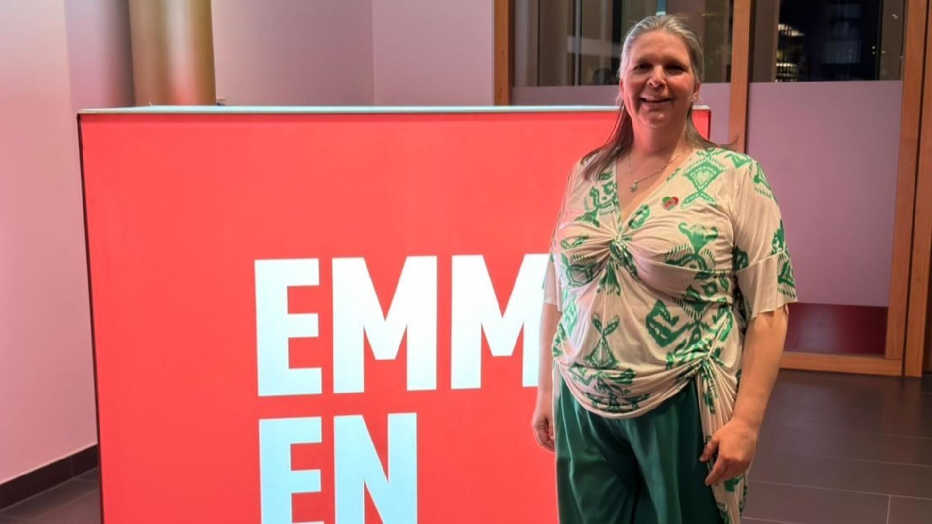 Mireille staat naast een groot blok met het EMMEN logo erop